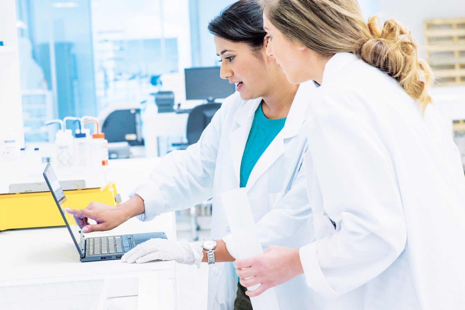 Women scientists in laboratory looking at surface tablet