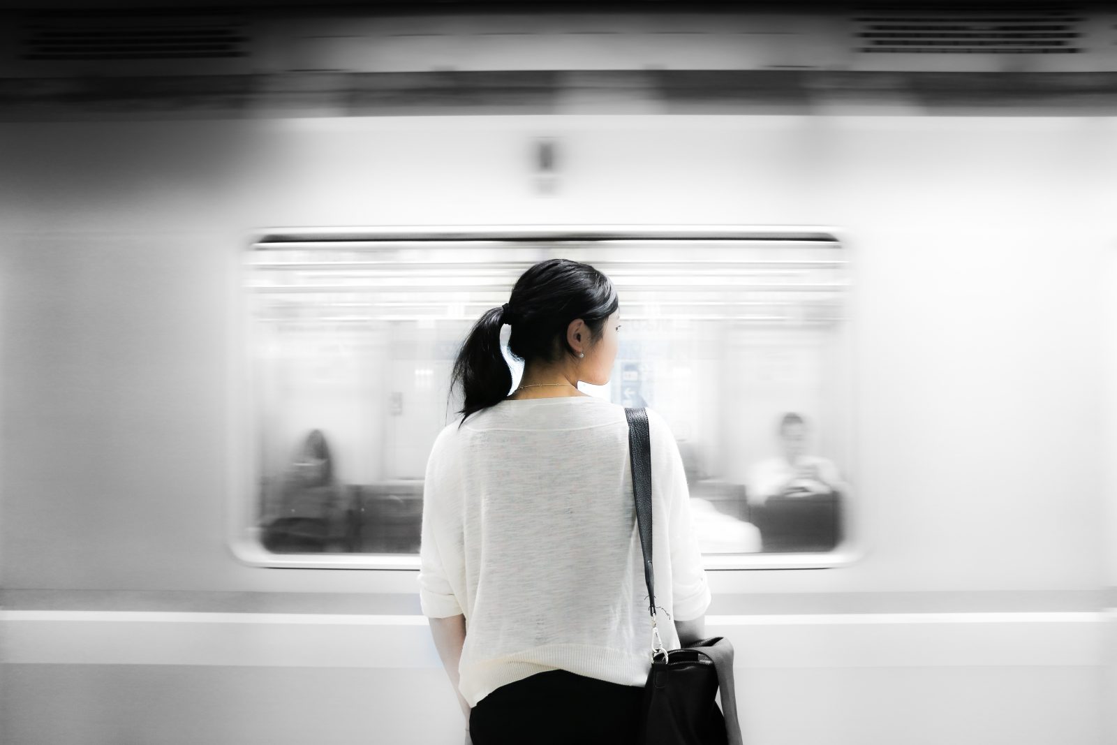 Woman standing on train platform as train rushes past