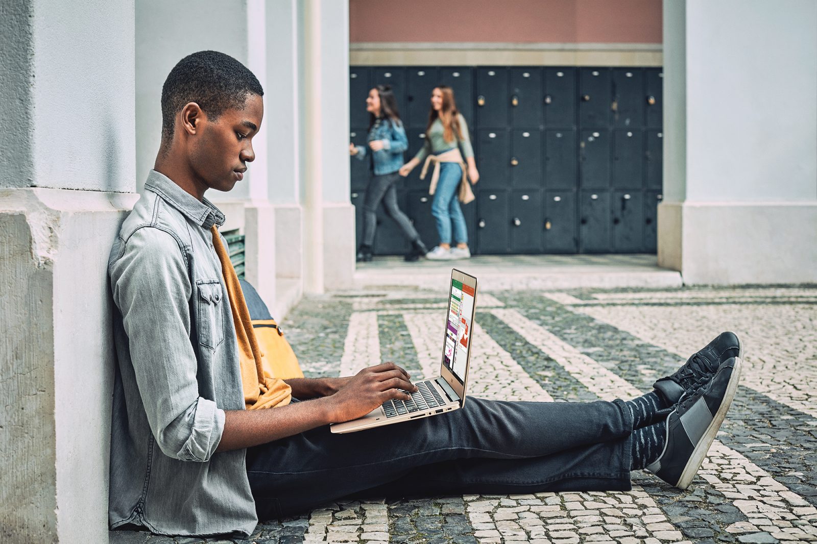 Male university student sitting on floor using laptop