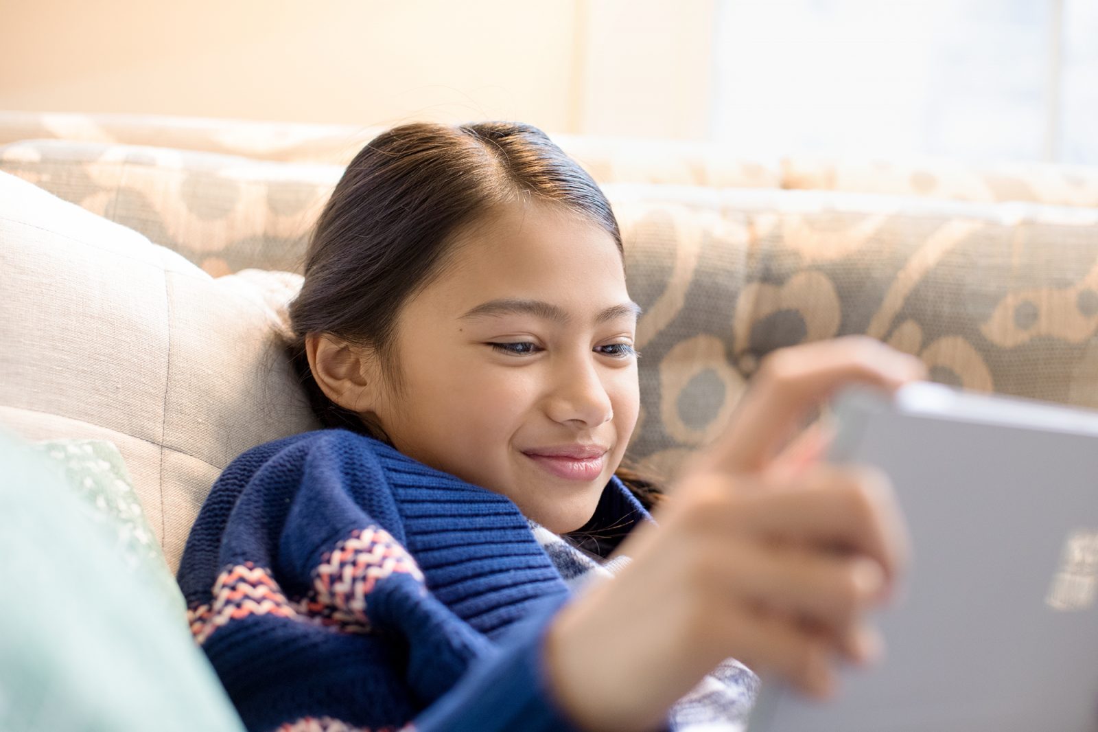Young girl using Microsoft Surface in family room