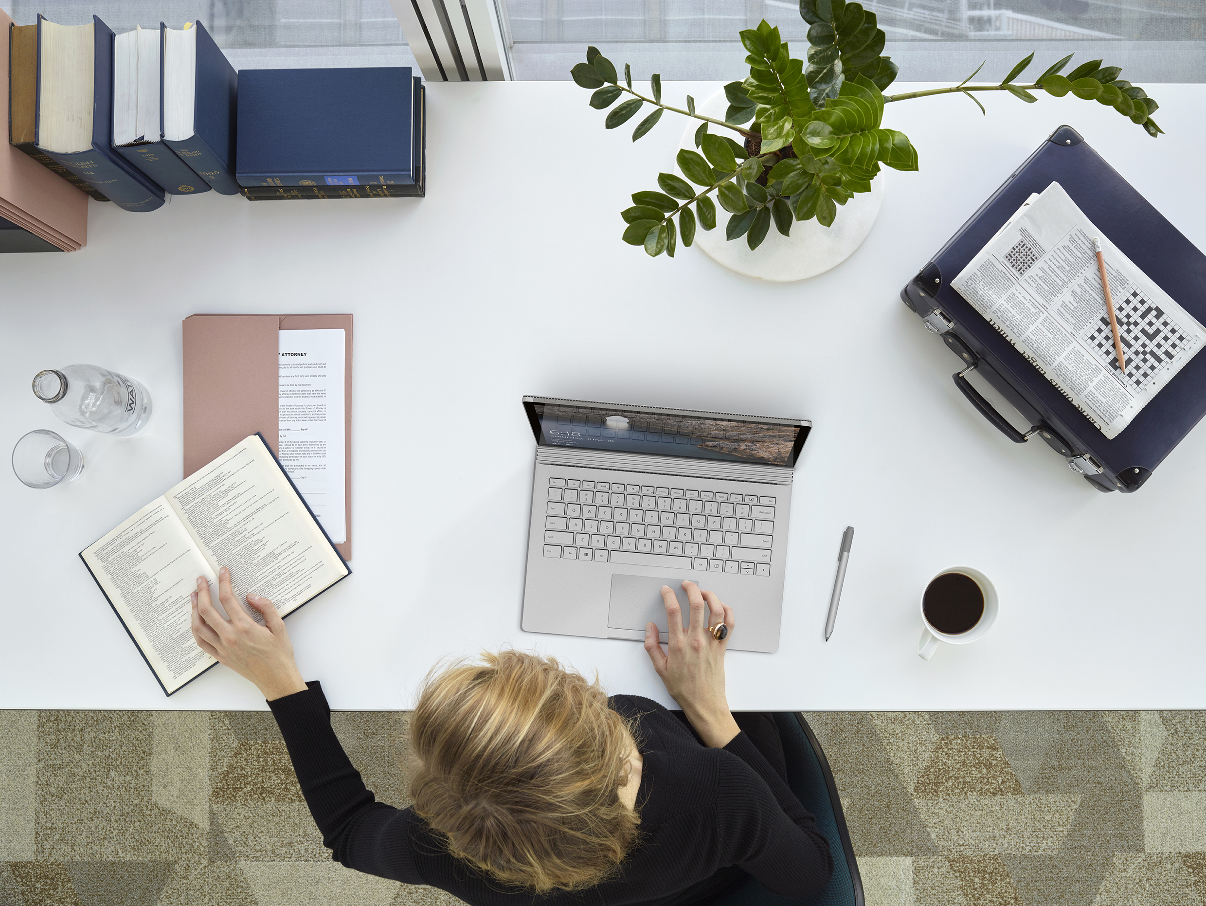 Overhead shot of woman at desk typing on Microsoft Surface device