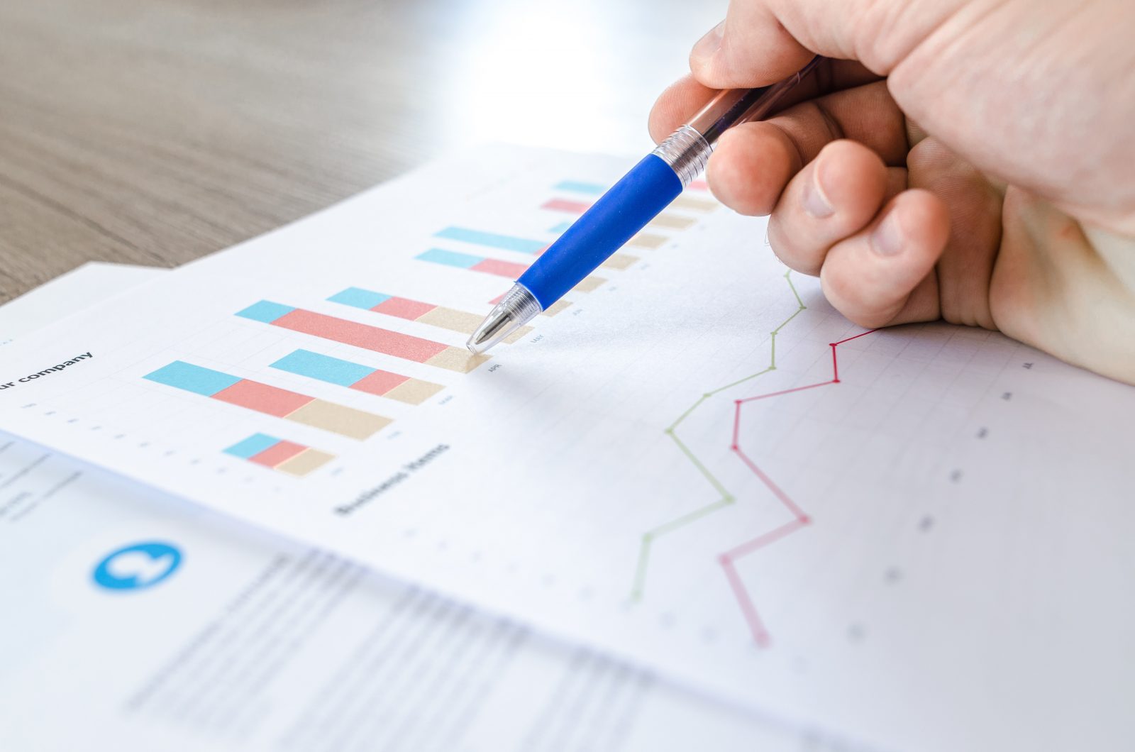 Close-up of hand holding pen and paper with data on it