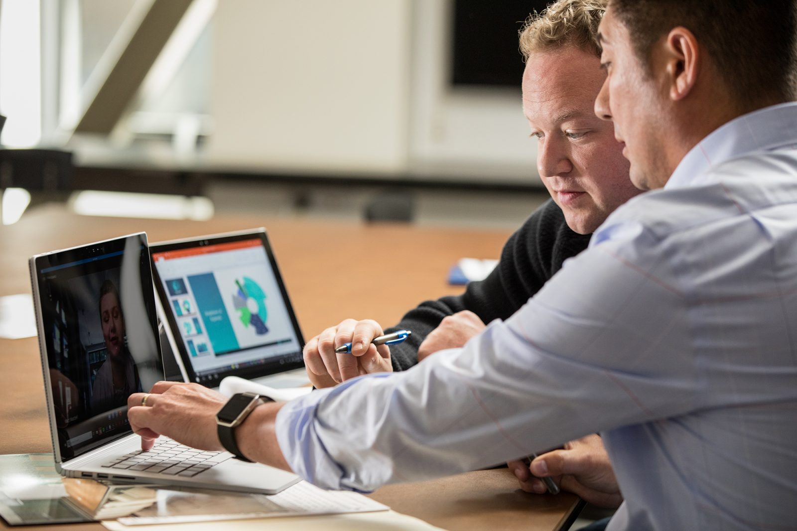 Two men in office hold Skype call with female colleague