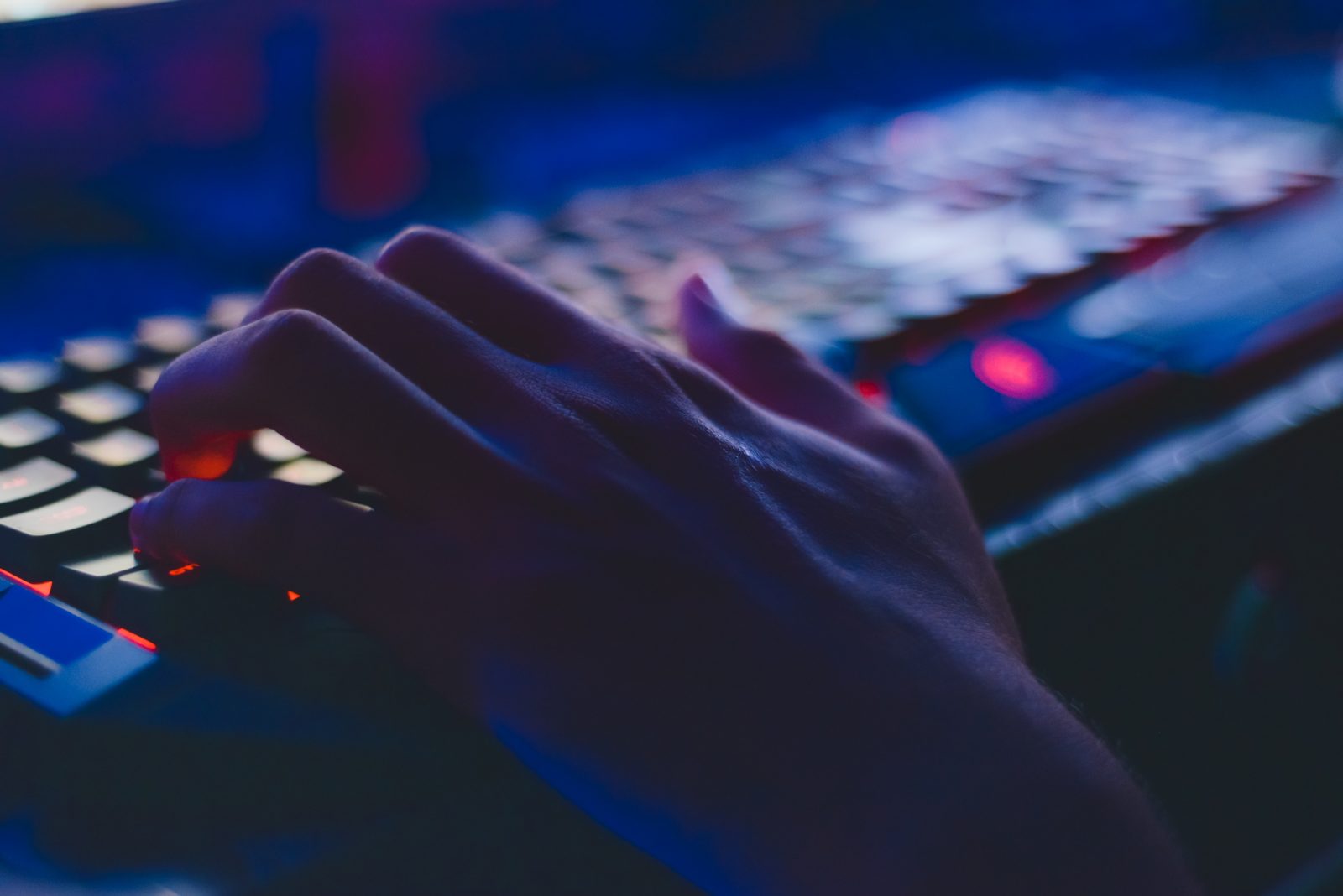 person typing on a keyboard in a dark room