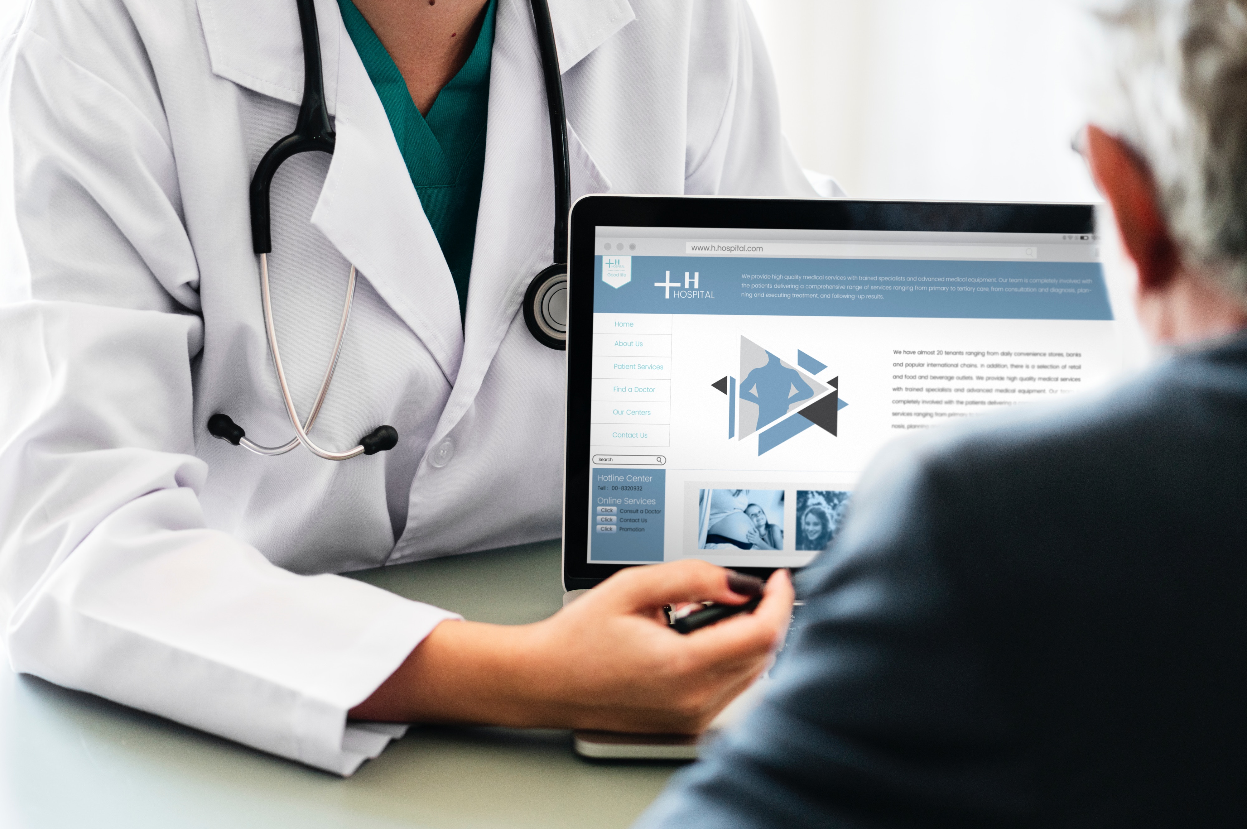 Doctor talking to patient, shows laptop with hospital website on the screen