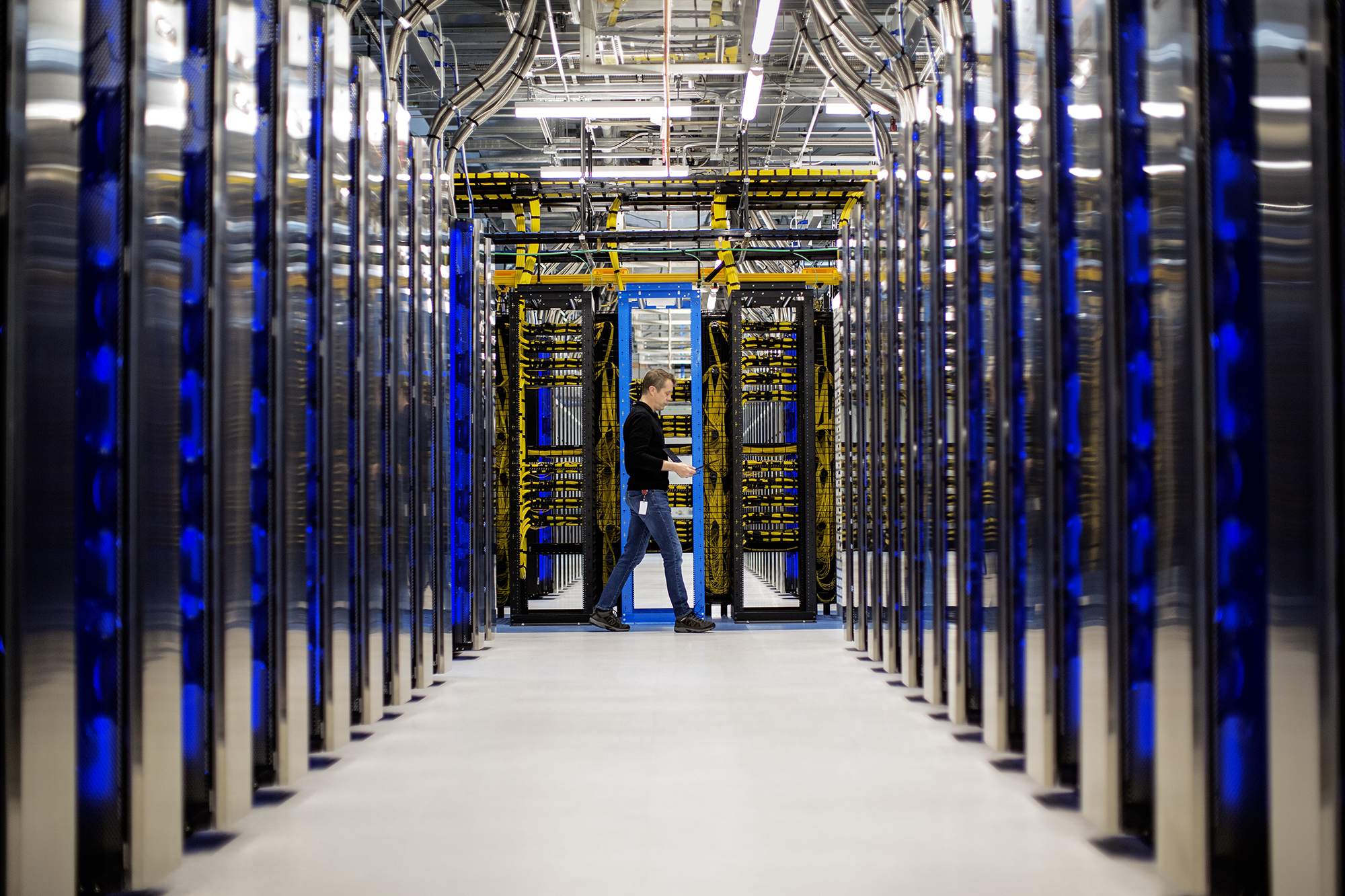 Man walking through room full of computer servers