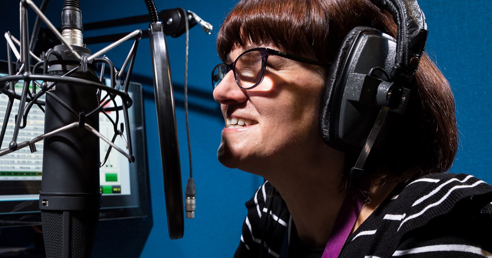 Corie Brown, from Channel 4, speaks into a microphone in a sound booth