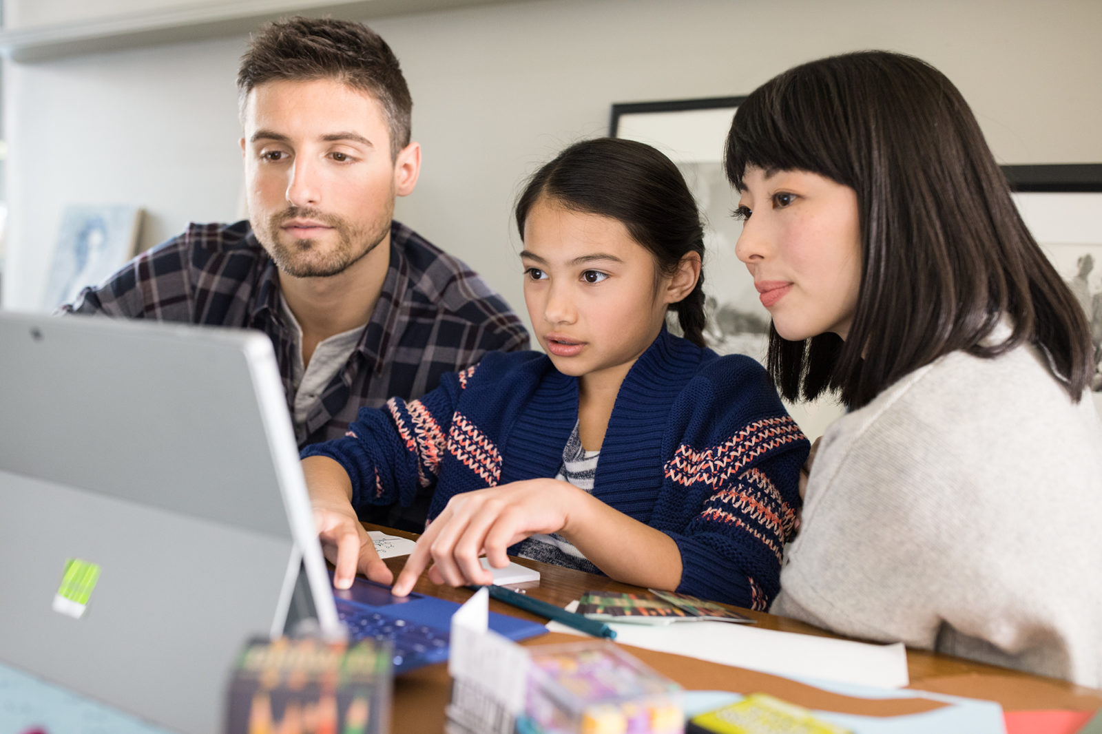 Male, female and child working together on laptop in family room. Homework, studying.
