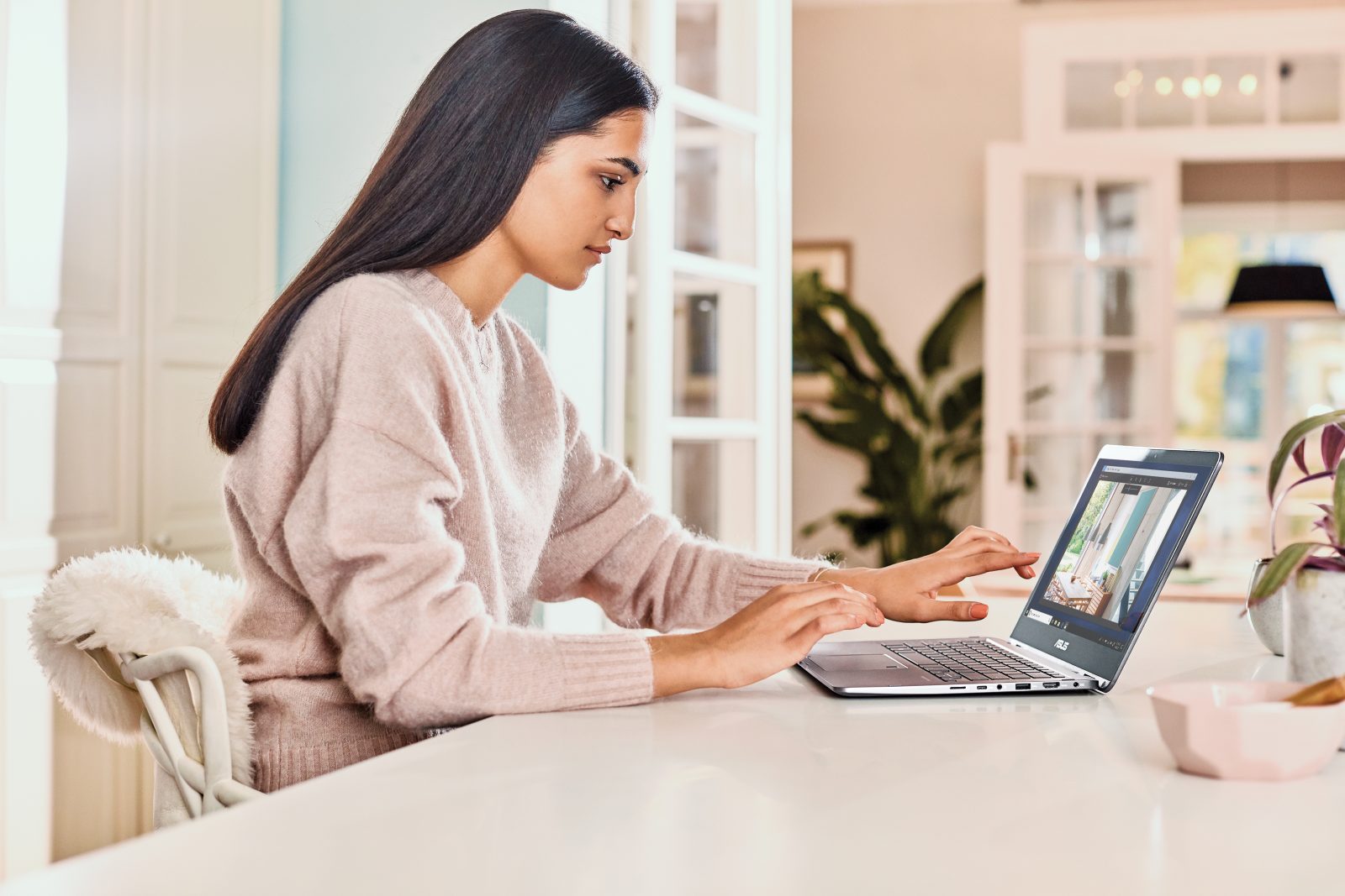 A teenage girl uses a laptop at home in her kitchen