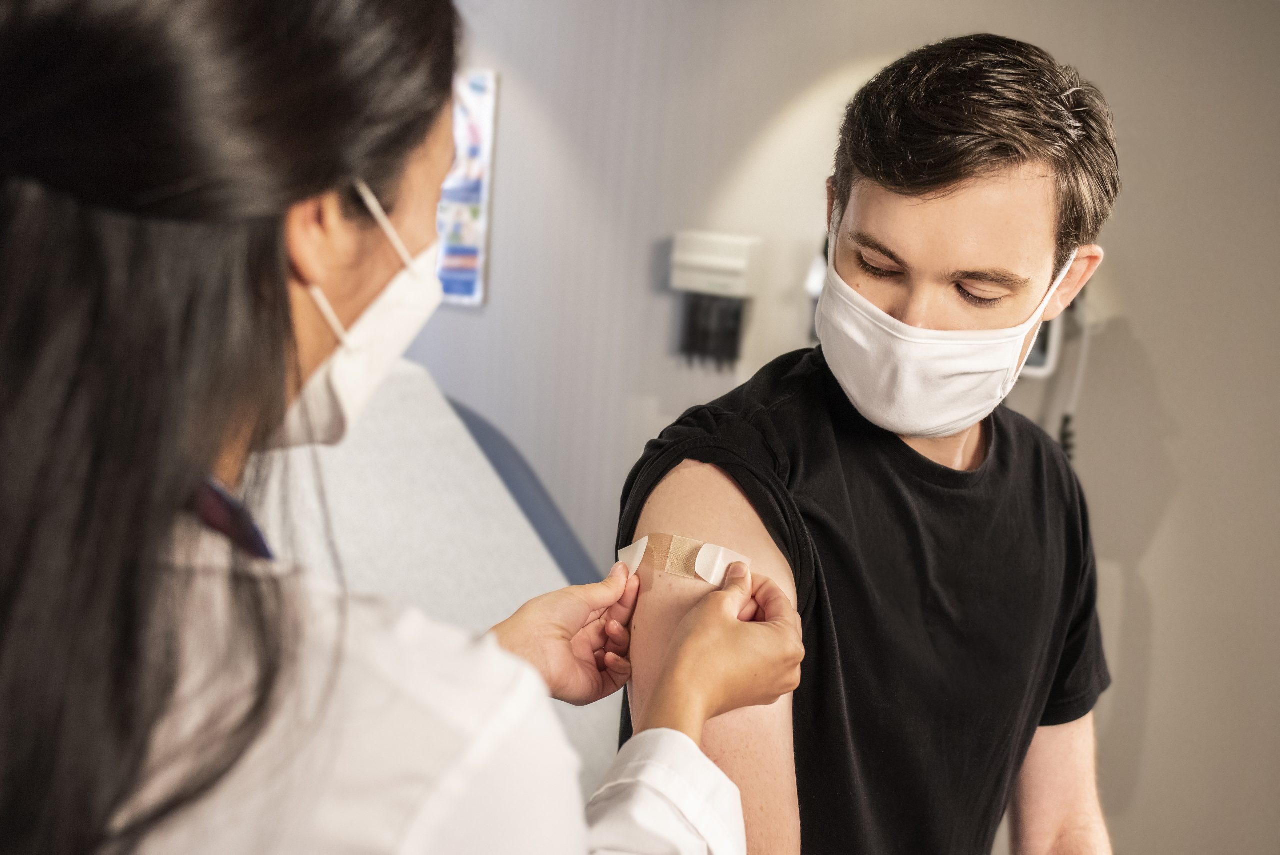 Doctor placing plaster on patient's arm after vaccination