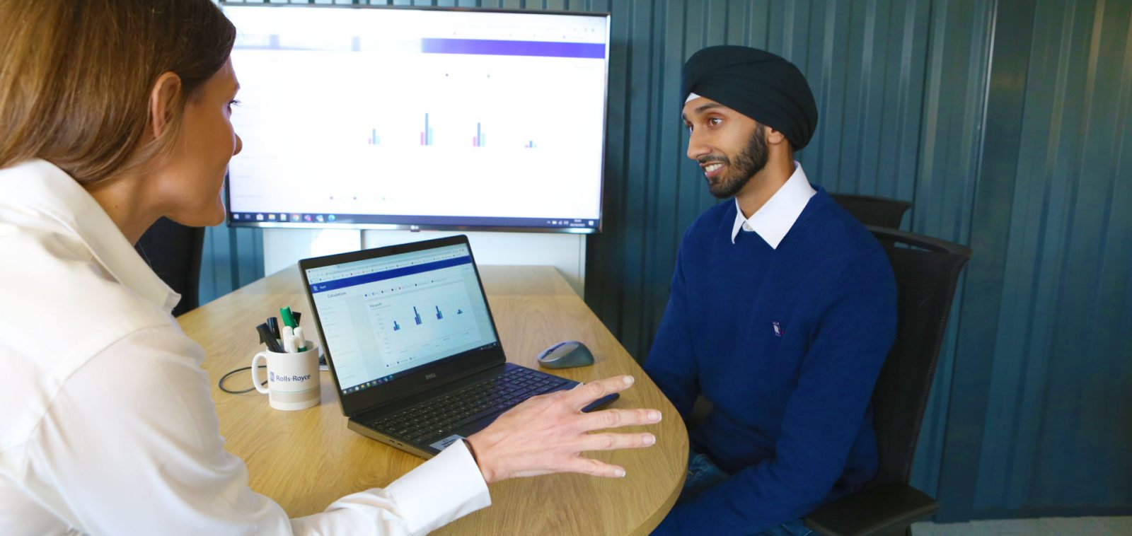 Two Rolls-Royce colleagues having a conversation beside an open laptop