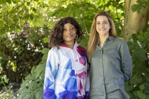 Two women standing in front of trees on a sunny day