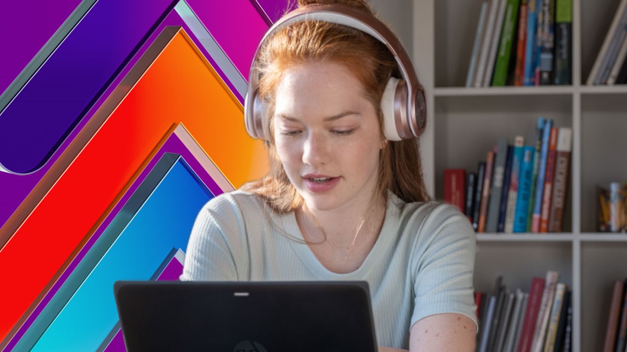 A woman wearing headphones looks at her laptop