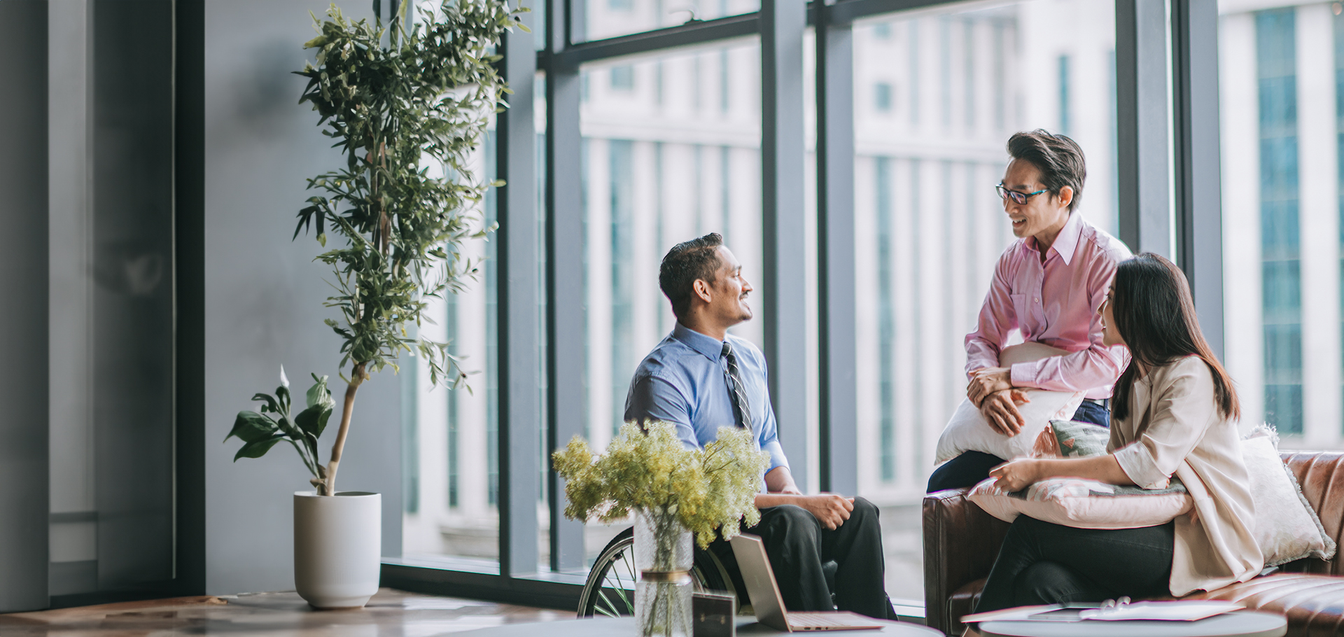 Man in a wheelchair talking to two office colleagues