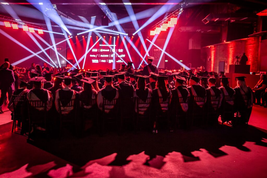 Rear view of UA92 graduates sitting wearing gowns and mortar boards