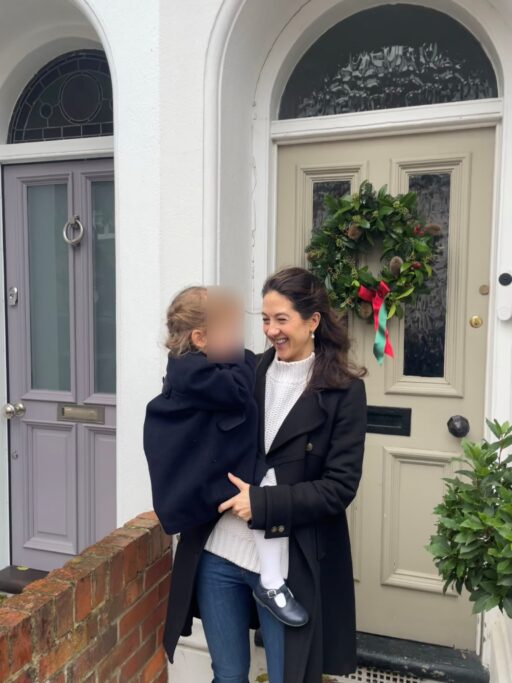 Hettie Holcroft holding her daughter in front of their house