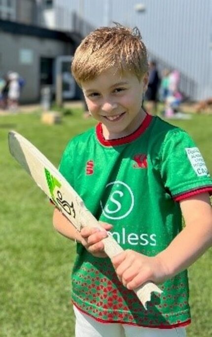 Freddie Dolan smiling and holding a cricket bat