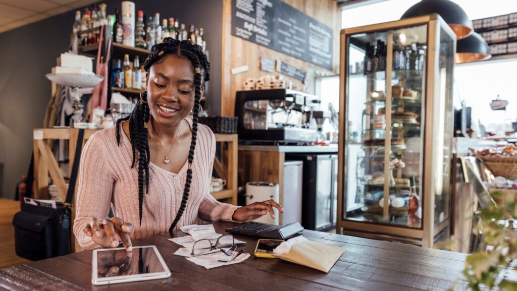 Young female small business owner working on tablet computer in her shop