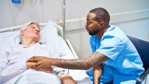 Male nurse comforting patient in hospital bed