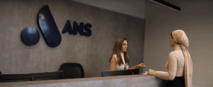 ANS logo behind receptionist talking to colleague