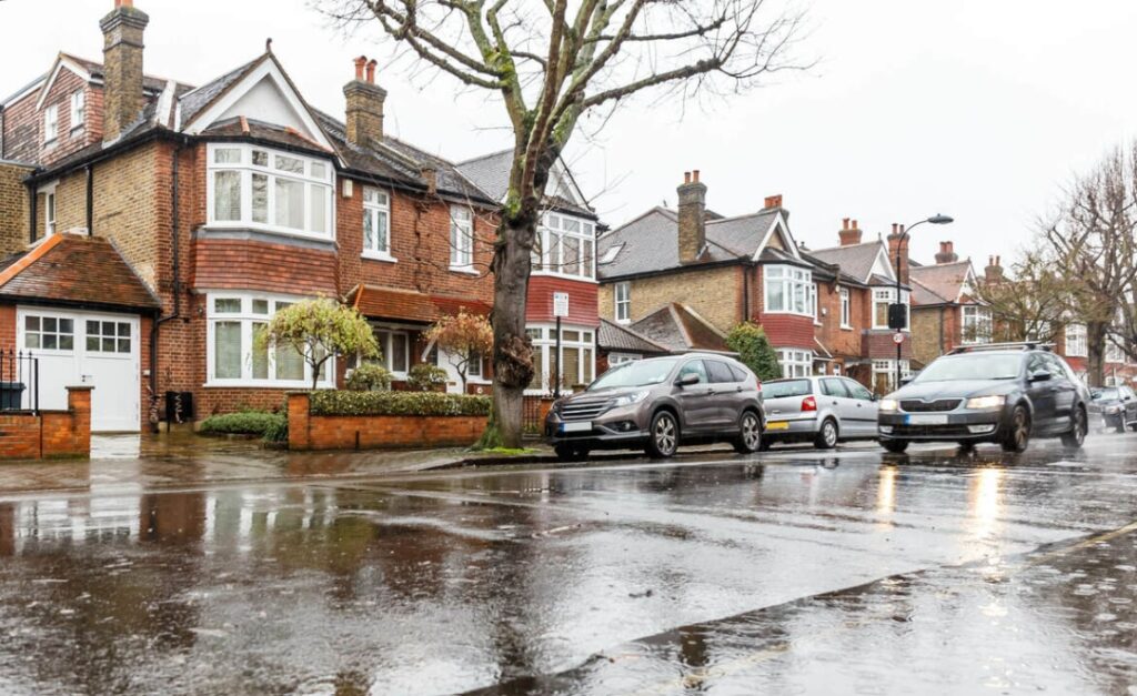 London residential street in the rain with cars passing