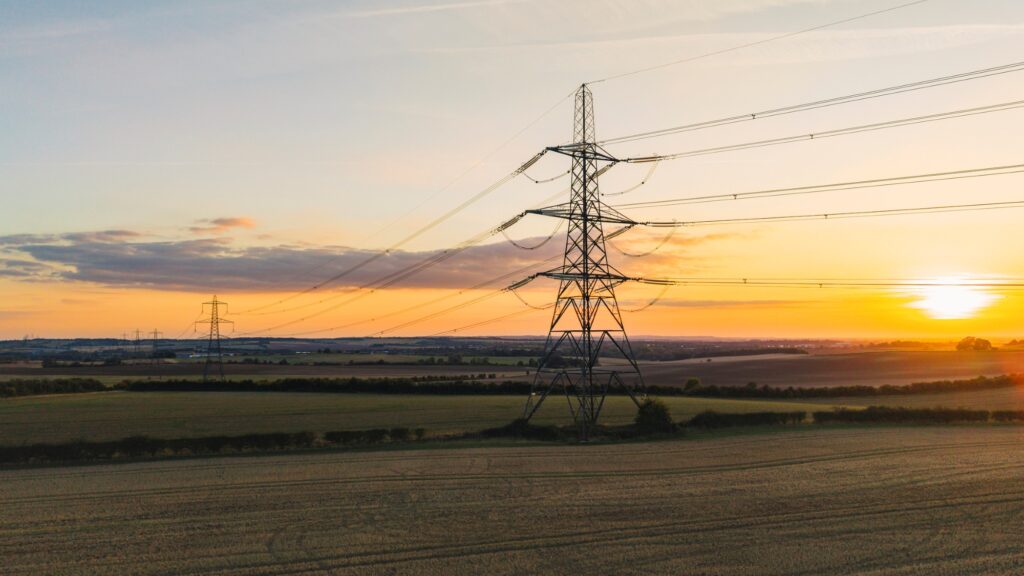 UK electricity pylons and cables in flat UK landscape at sunset