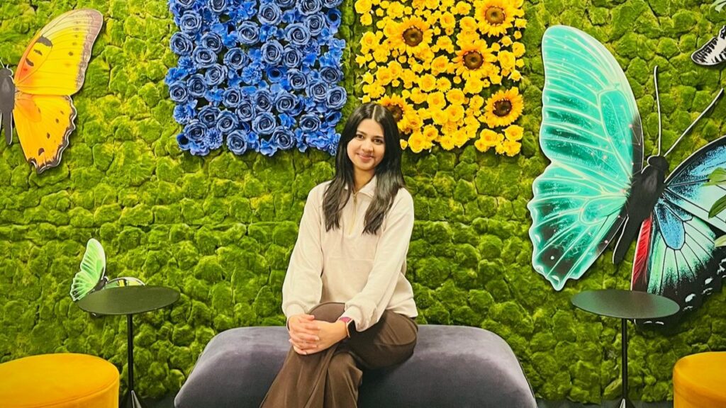 Microsoft apprentice Aarushi Karankal sitting before a colourful backdrop in a Microsoft office