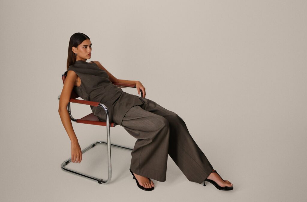 Female fashion model wearing trouser suit and reclining on a chair