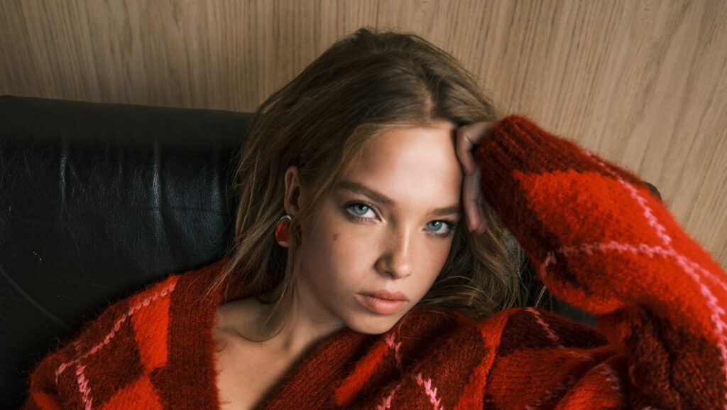 Young female fashion model wearing red and orange chunky knit sweater