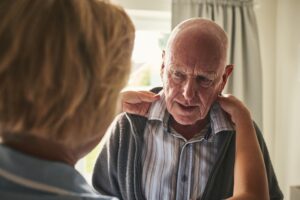 Carer helping elderly man with dementia get dressed